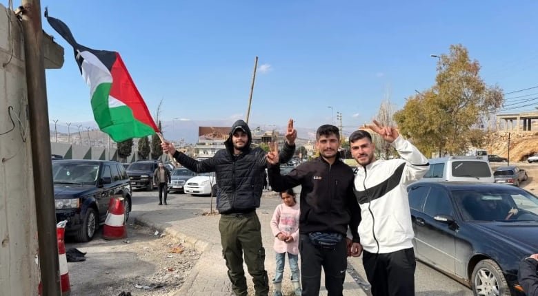 Young men make the victory sign and hold up a flag. 