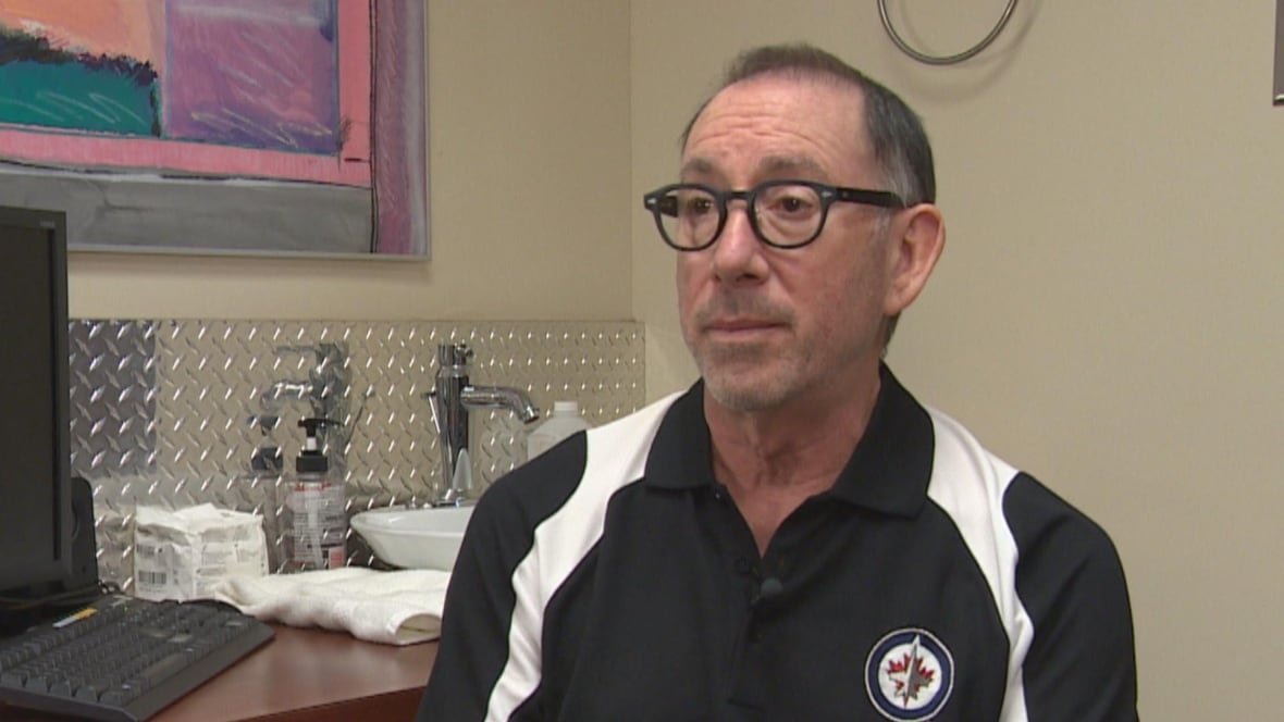 A man with glasses sits in medical office.