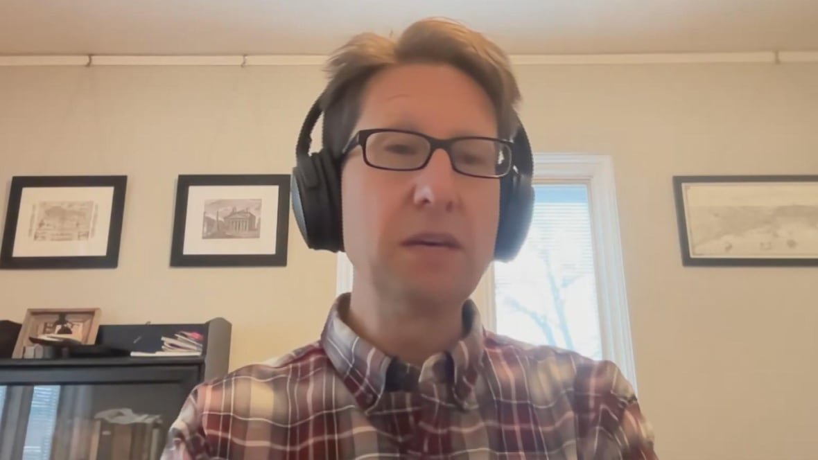 A man sitting in an office wears headphones.