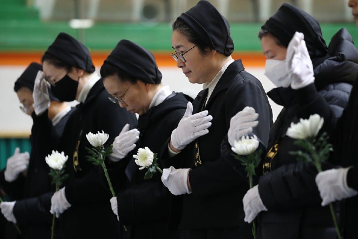 Nuns hold white flowers and pray at a memorial for plane crash victims in South Korea.