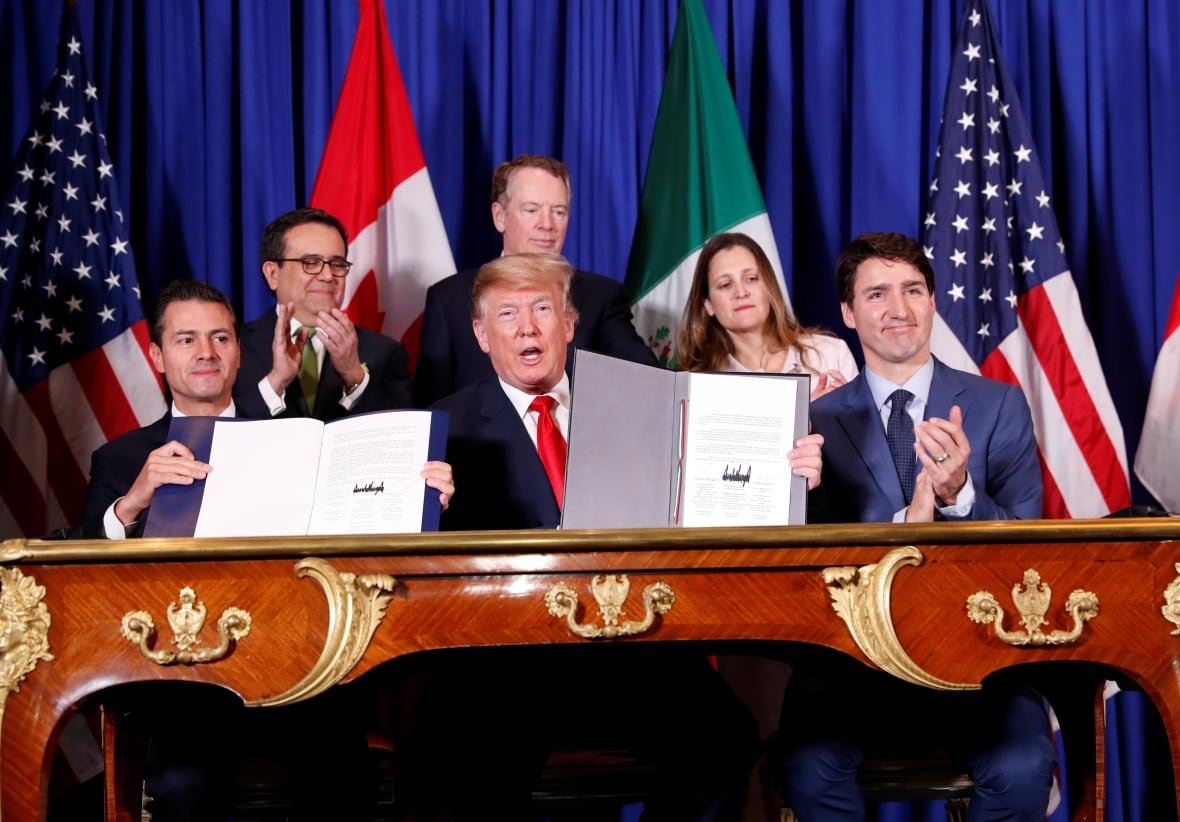 U.S. President Donald Trump and Mexico's President Enrique Pena Nieto show off signatures on documents while Prime Minister Justin Trudeau applauds. 