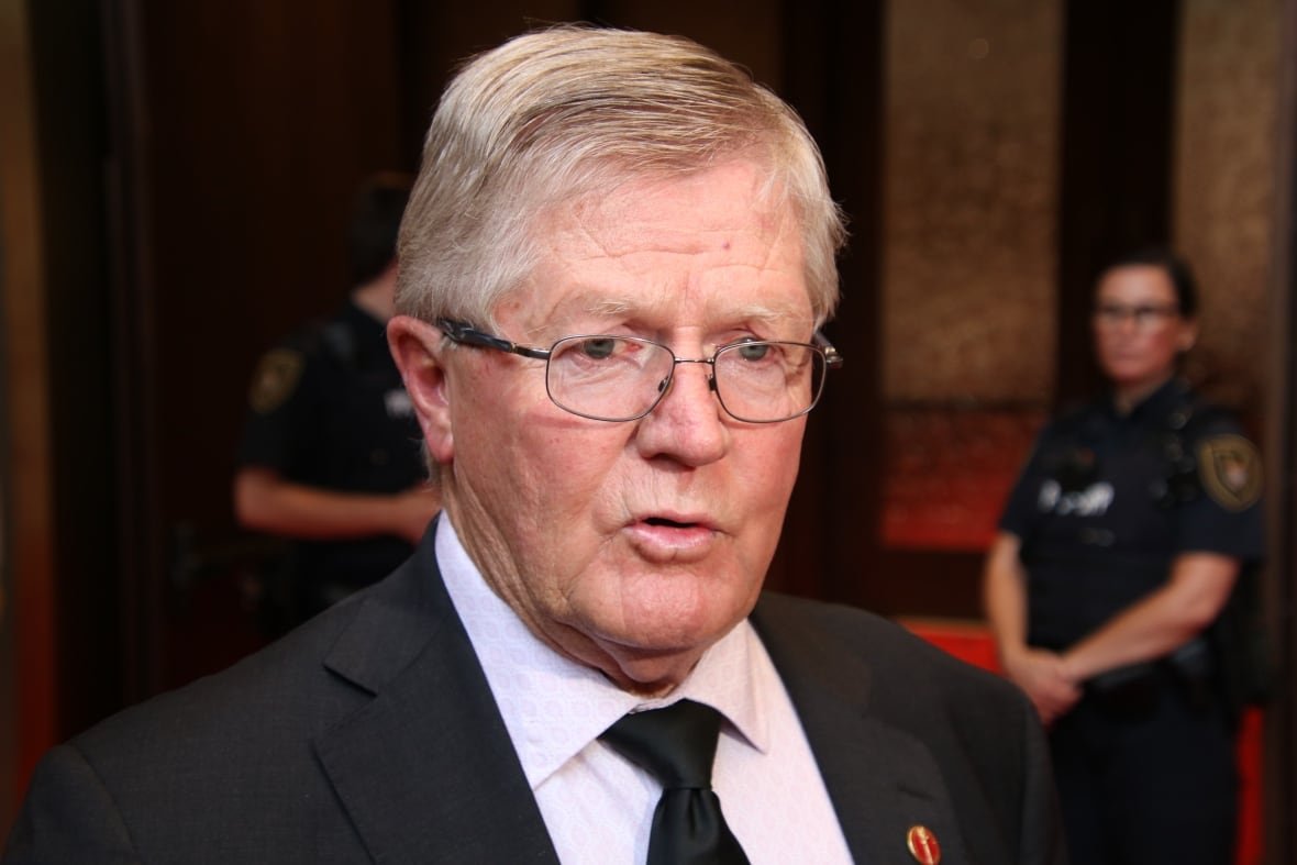 A man wearing glasses is shown in a shirt and tie.