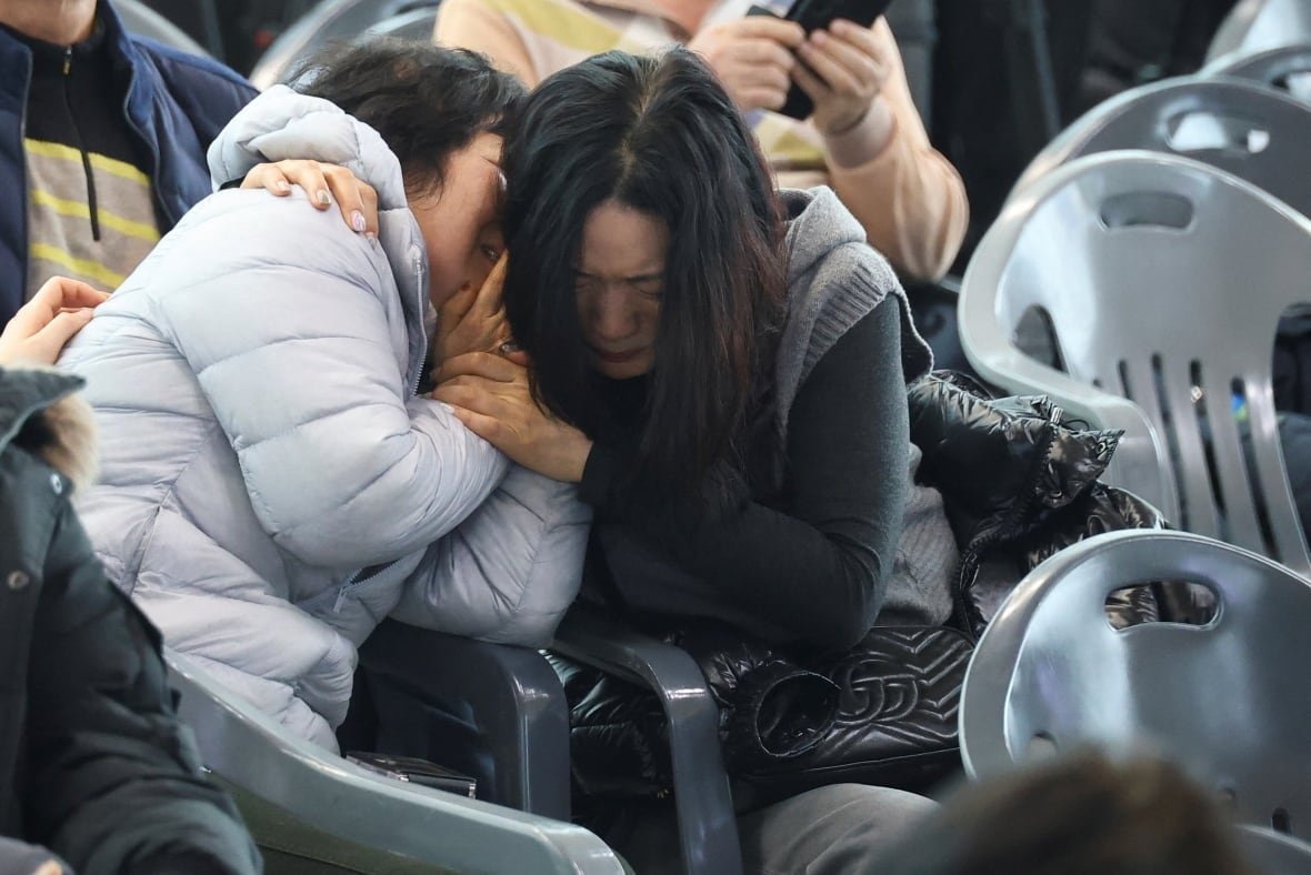 Two women sitting in chairs cry and hug eachother. 