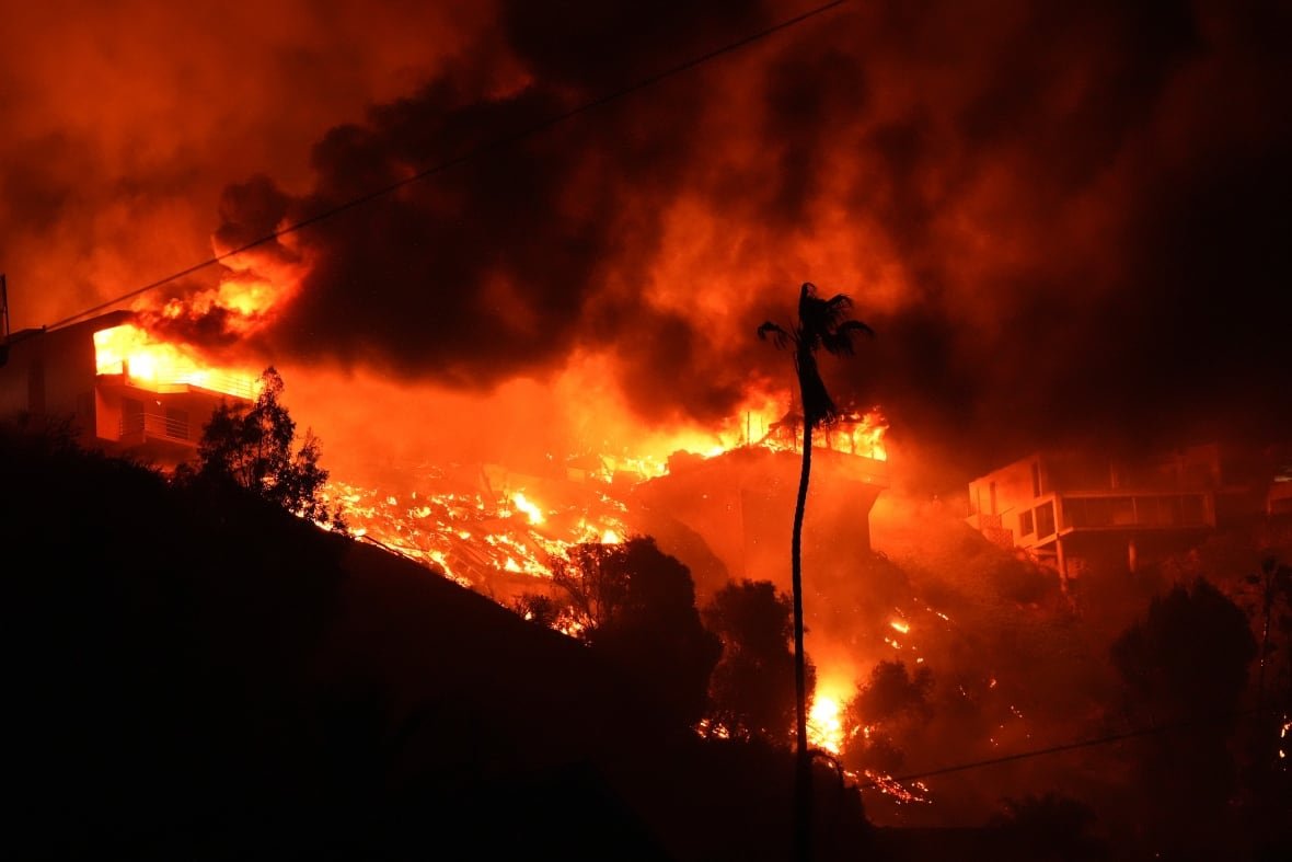 Orange flames burn large homes on a hilltop