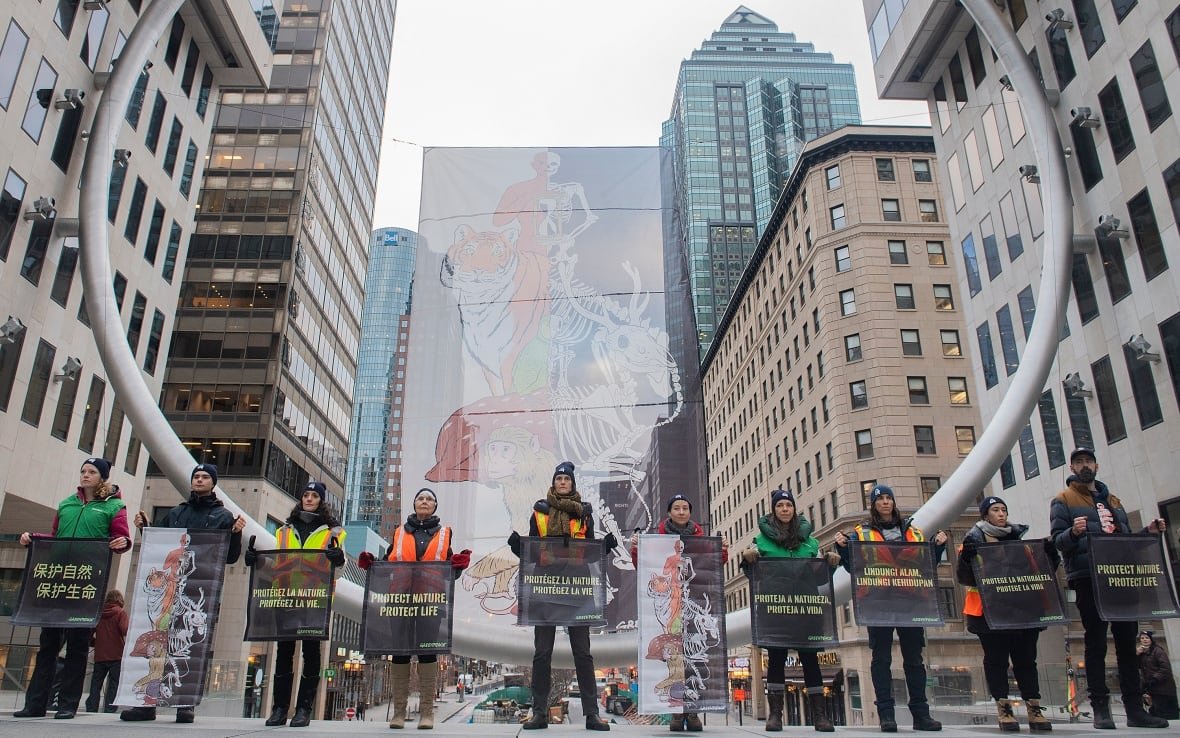 People holding banners stand in a row among tall buildings.