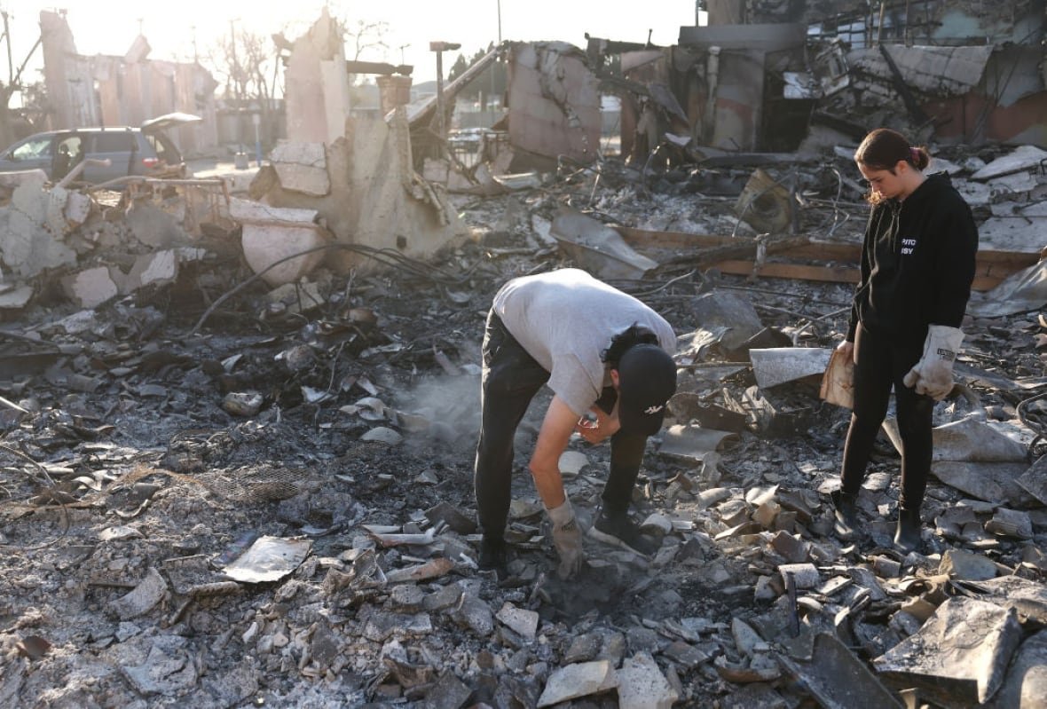 Two people pick through the burned-out remains of a Jewish temple and centre.