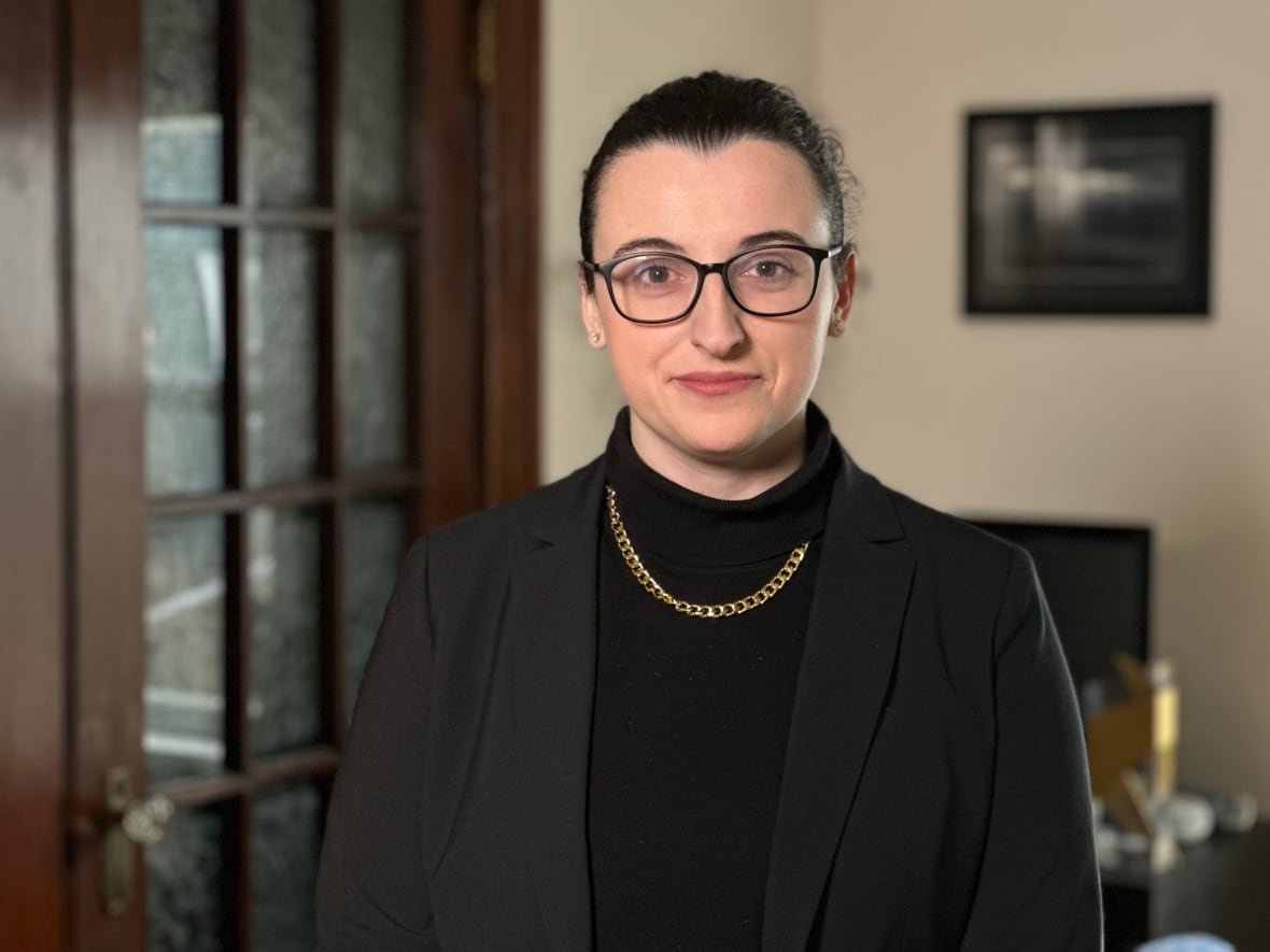 A woman wearing a black blazer and a black sweater poses for the camera.