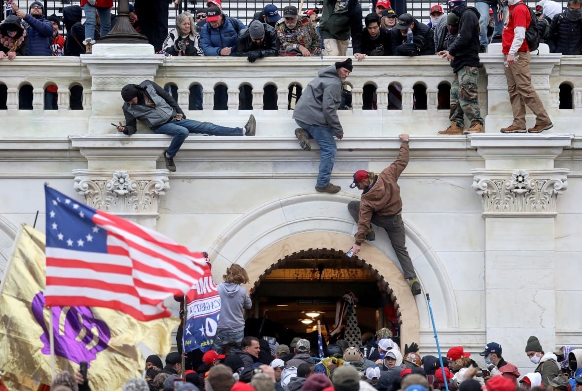 A mob climbs the facade of a large building.