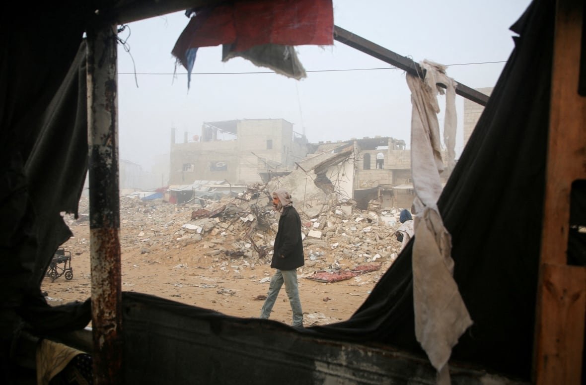 A person walks amid the rubble of destroyed buildings.